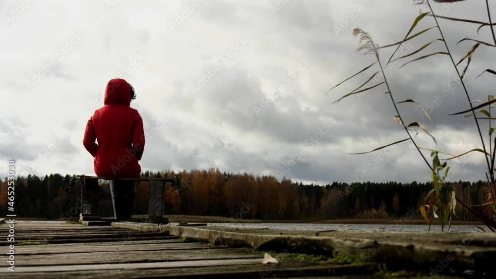 Woman in red jacket looks at the lake and sunset. Woman in red jacket looks at the lake and sunset.