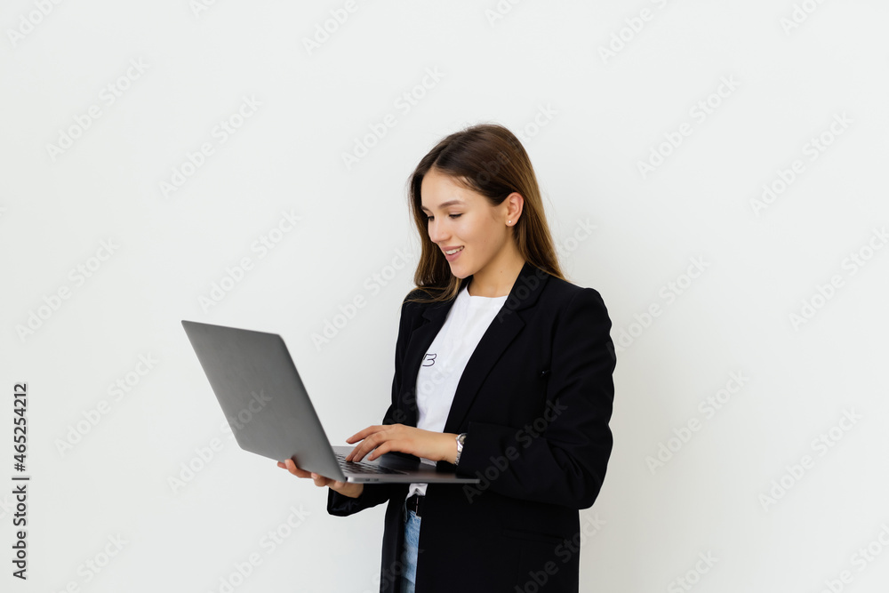 Portrait of a smiling businesswoman standing with laptop and looking at camera isolated on a white background Portrait of a smiling businesswoman standing with laptop and looking at camera isolated on a white background