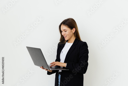 Portrait of a smiling businesswoman standing with laptop and looking at camera isolated on a white background