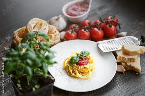 italian pasta bolognese with grated parmesan and basil close-up ingredients in the background