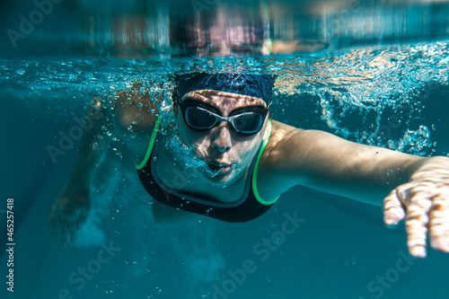  Female swimmer in sports outfit at the swimming pool.Underwater photo. 