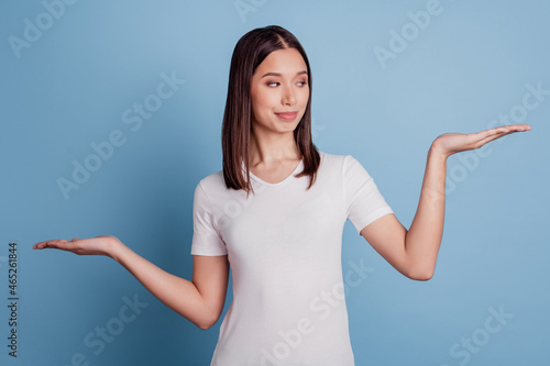 Photo of nice curious smart girl palms weighing invisible objects blank space on blue background photo