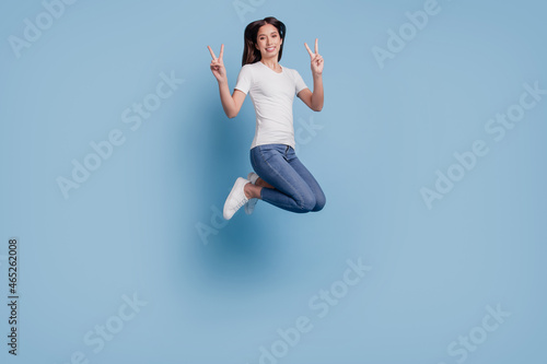 Portrait of lovely inspired friendly lady jump show two v-signs on blue background