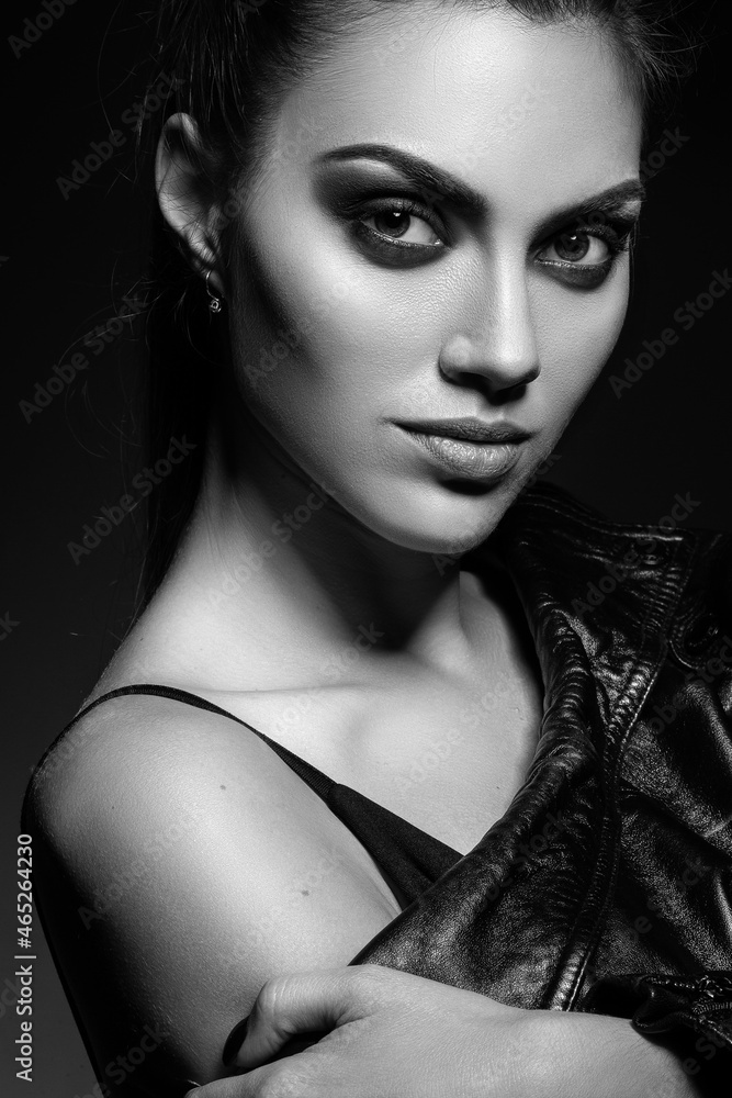 Fashionable studio portrait of a beautiful young model on a black background. Low key