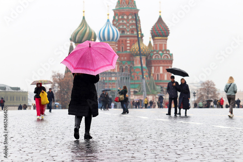 Rain in Moscow, woman with pink umbrella walks on people background on Red square against the St Basil Cathedral photo