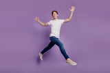 Full body profile side photo of young man good mood go walk run jump isolated on violet color background
