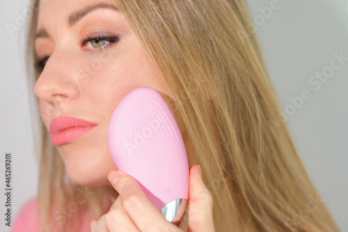 Young woman use facial massage pink brush