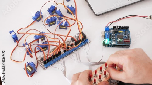 A male programmer creates robotics, an arduino board controls servo motors. DIY mechanics, programming through codes on a laptop. Technologies of the future. controls
