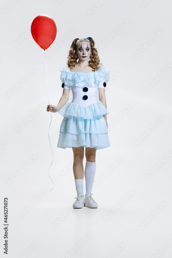 Conceptual image of charming young girl in Halloween costume of movie character with spooky facial expression isolated over blue background Conceptual image of charming young girl in Halloween costume of movie character with spooky facial expression isolated over blue background