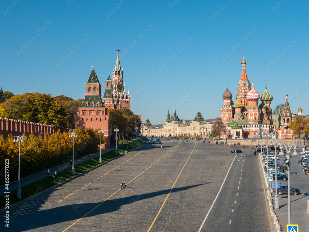 View of the Kremlin and St. Basil's Cathedral from the Moskvoretsky bridge against the blue sky. People walk along Red Square. Moscow, Russia. View of the Kremlin and St. Basil's Cathedral from the Moskvoretsky bridge against the blue sky. People walk along Red Square. Moscow, Russia.