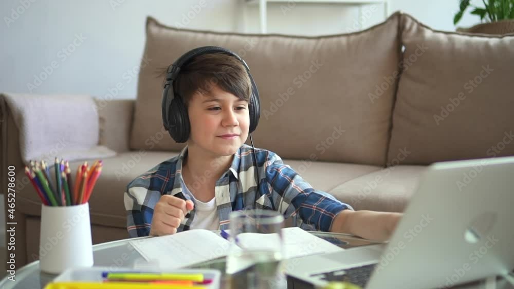 Boy school student greet teacher, wave hand for tutor and start online lesson Spbd. Smiling elementary student sit by sofa with laptop virtual leaning. Concept homeschooling, notebook, headphone Boy school student greet teacher, wave hand for tutor and start online lesson Spbd. Smiling elementary student sit by sofa with laptop virtual leaning. Concept homeschooling, notebook, headphone