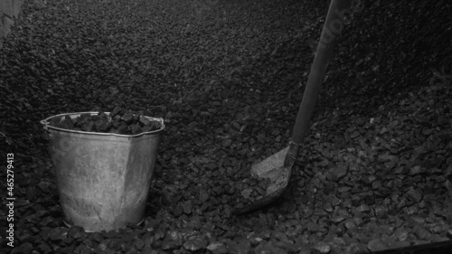 A pile of brown coal, a bucket of coal and a shovel. Fuel for heating in winter