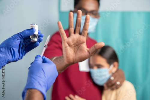 Фотография Selective focus on coronavirus vaccination bottle - Concept of Parents vaccine hesitancy for children, showing by saying no or stop gesture to vaccine with hand at hospital
