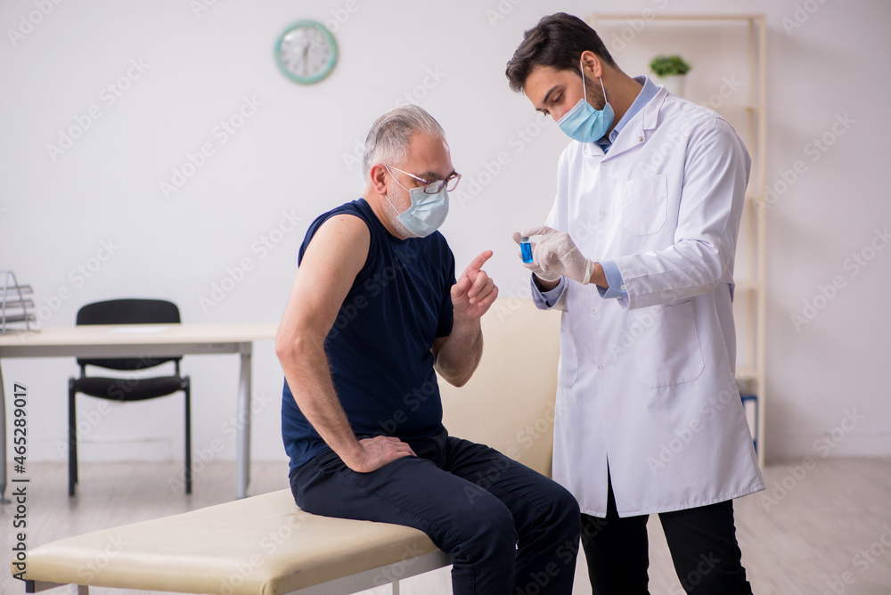 Old male patient visiting young male doctor in vaccination conce Old male patient visiting young male doctor in vaccination conce