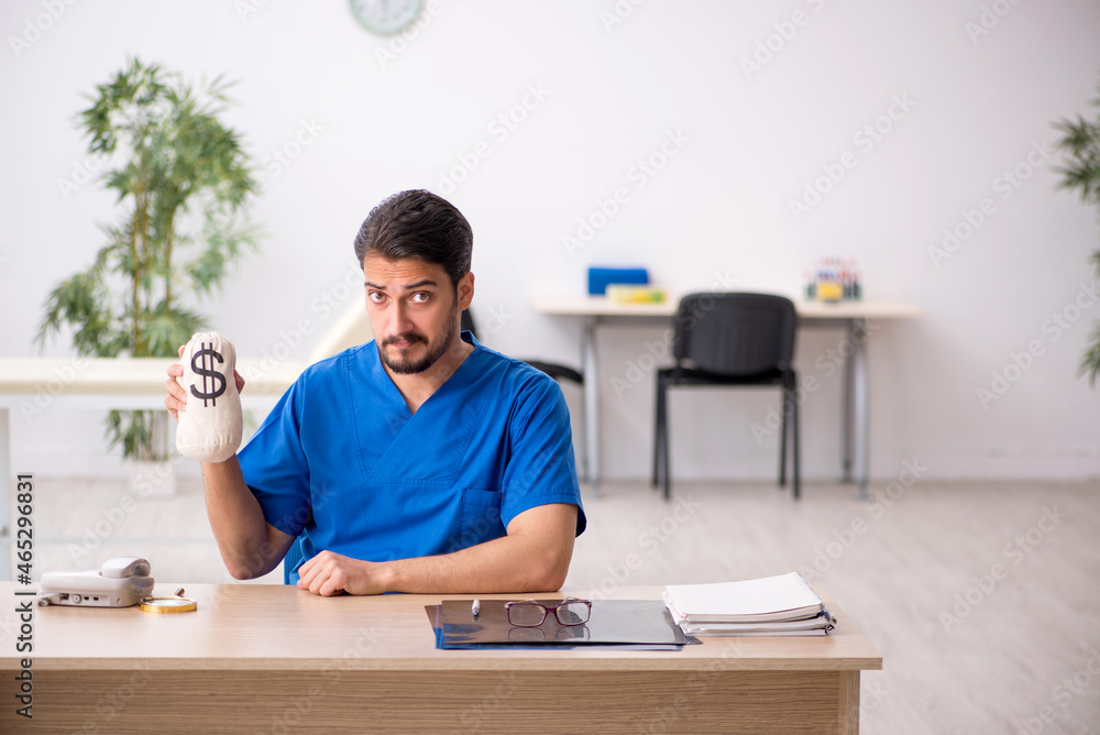 Young male doctor in remuneration concept Young male doctor in remuneration concept