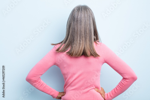 middle age gray hair woman feeling confused or full or doubts and questions, wondering, with hands on hips, rear view