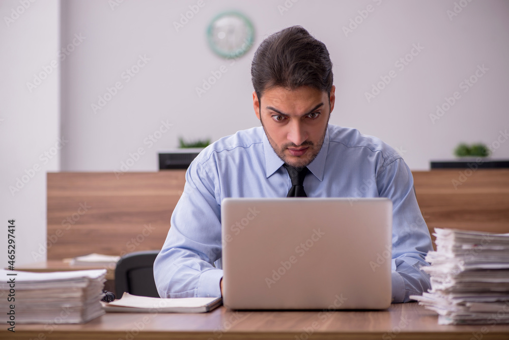 Young male employee and too much work in the office Young male employee and too much work in the office