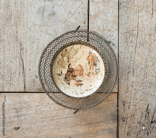 Vintage fayance wall plate with wire frame on a rustic wooden table photo