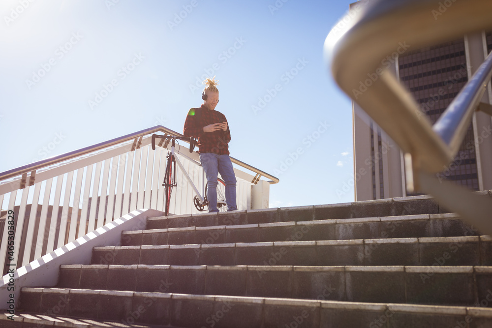 Thoughtful albino african american man with dreadlocks wearing headphones using smartphone Thoughtful albino african american man with dreadlocks wearing headphones using smartphone