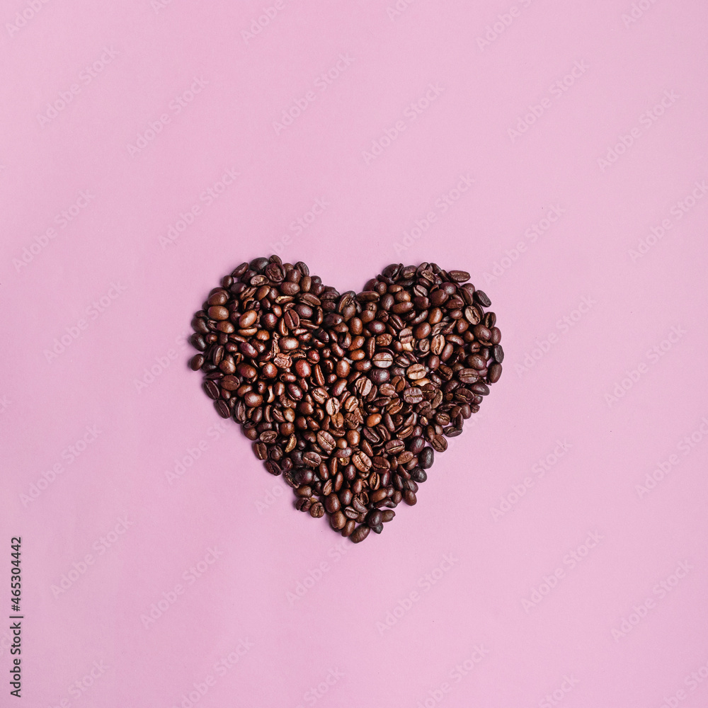 Freshly roasted heart shaped brown coffee beans with copyspace on pink color background,top view Freshly roasted heart shaped brown coffee beans with copyspace on pink color background,top view