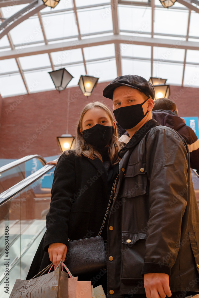 Black friday pandemic concept. Young couple in black masks at the mall Black friday pandemic concept. Young couple in black masks at the mall