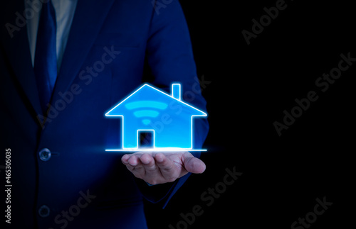 businessman holding a glowing house icon Real estate, investment and finance concepts, banking and savings.