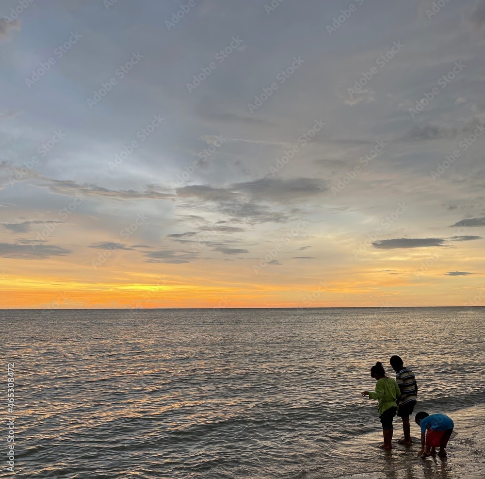 Fototapeta premium kids playing sea water during sunset by the beach