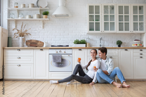 Love couple sitting on the floor at kitchen with juice.