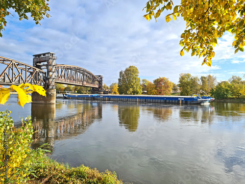 historische Eisenbahnbrücke Magdeburg im Herbst mit Schubschiff