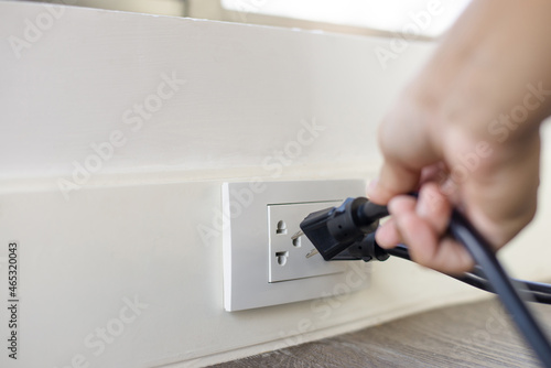 In the hand of a young man holding a power cord to unplug unused appliances to save energy, save money. photo