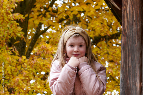 Beautiful little girl in the autumn in the park. The child plays in the playground.