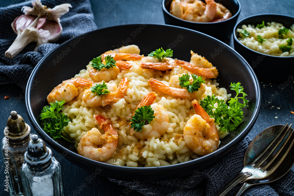 Risotto with prawns, chili and parsley on wooden table

