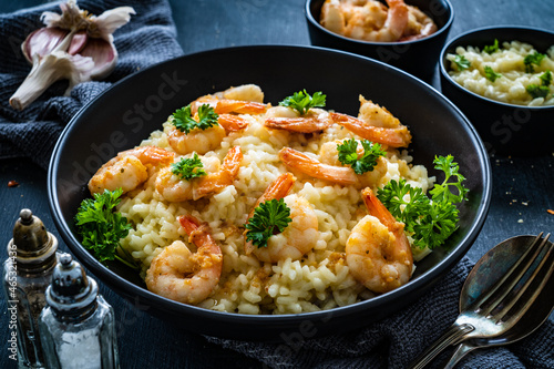Risotto with prawns, chili and parsley on wooden table

 photo