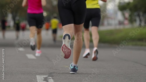 Feet of marathon contestant running on asphalt road in city. Following shot of active people taking part in sports competition. Concept of healthy lifestyle