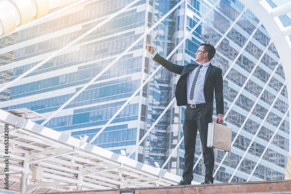 Young businessman standing and point to target business success with cityscape background. Young businessman standing and point to target business success with cityscape background.
