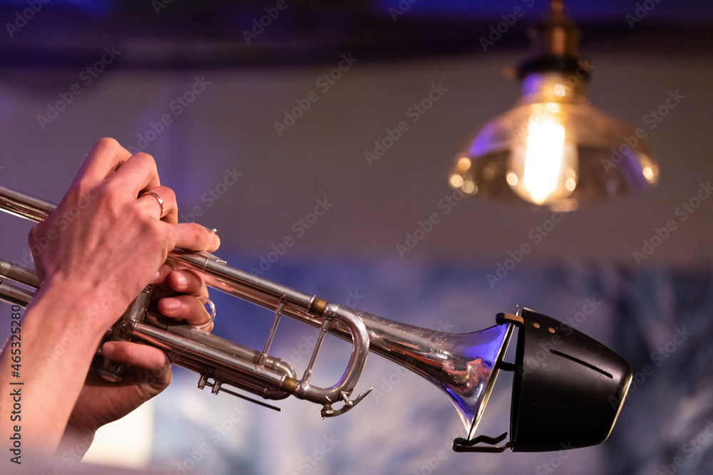 Obraz premium A musician playing a silver plated piston trumpet with a bucket mute during a jazz gig in a bar
