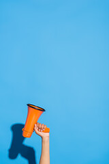 partial view of african american woman with orange megaphone on blue