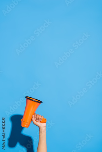 partial view of african american woman with orange megaphone on blue