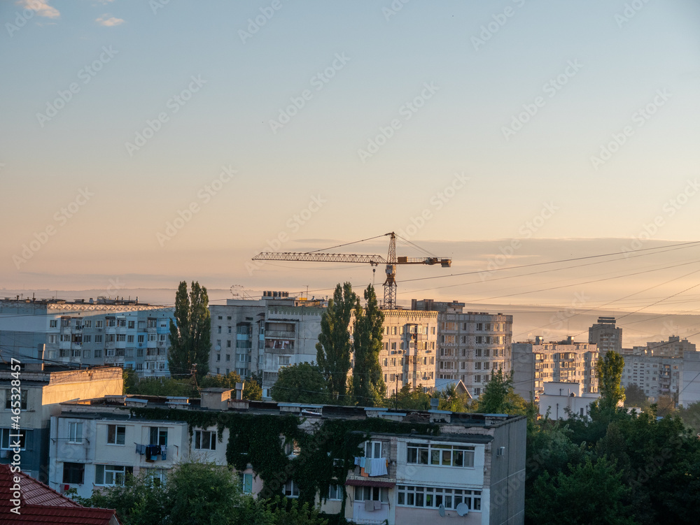 Construction of high-rise buildings in the city. Construction crane over the roofs of houses.