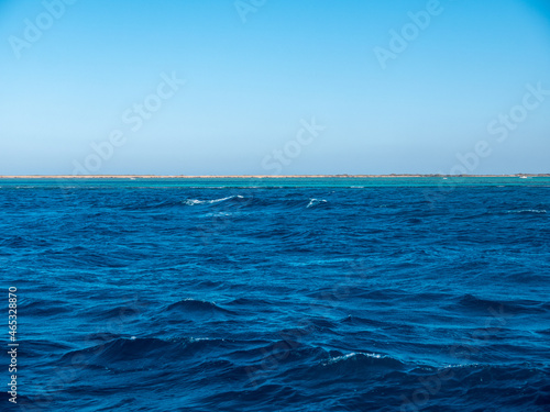 Panorama of sea waves against the backdrop of the coast and blue sky.