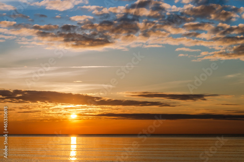 Sunset over the sea. Reflection of sunlight in the sea waves. The sky in the sunset rays.