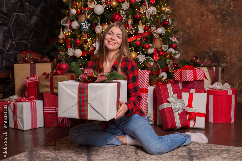Young beautiful woman near a christmas tree with gifts in a luxurious interior Young beautiful woman near a christmas tree with gifts in a luxurious interior