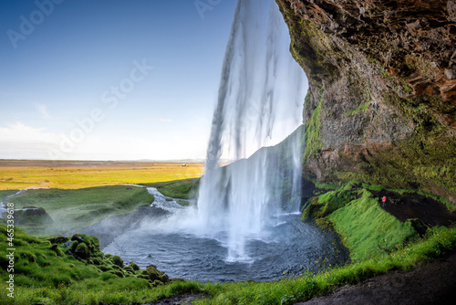 Walking behind Seljalandsfoss waterfall in summer, Iceland © Delphotostock