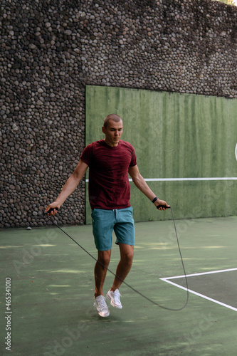 man jumping rope on the tennis court © alexzhilkin