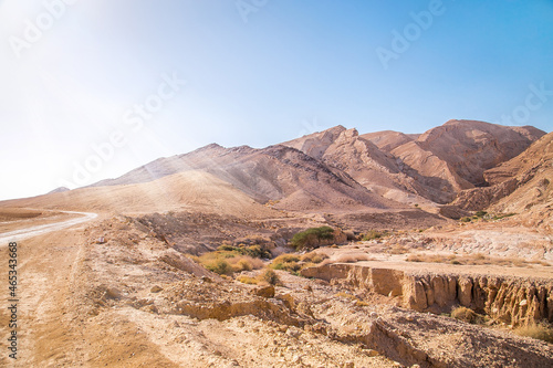 Rocky and dusty mountains of the Negev Desert in Israel. Breathtaking landscape with huge stones on top of the hillside near the peak of mountain range at sunbeam. Summer Landscape view with sunlight.