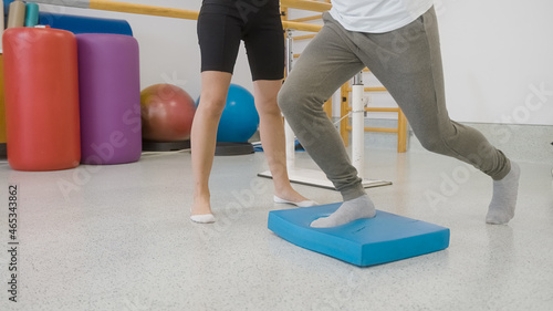 Male patients legs doing balance pad exercises with the assistance of a female therapist. photo