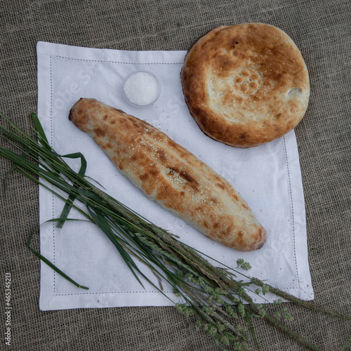 Round and long freshly baked pita bread on a white linen napkin, top view