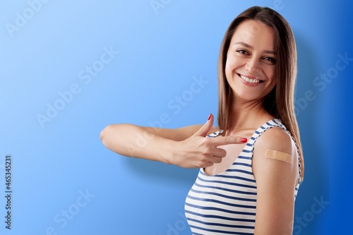 Happy young attractive beautiful woman showing bandage happily after receive covid-19 antivirus vaccination