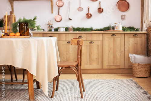 Stylish dining room in rustic style. Cozy Wooden kitchen decorated Christmas or new year. On table fir branche in vase  Xmas cookies. Interior design scandinavian kitchen with round table and chair. 