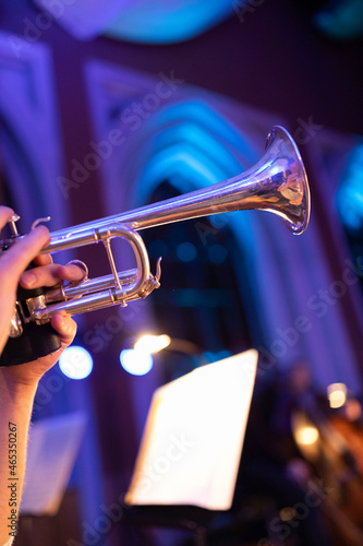 Canvas Print A person playing a silver plated trumpet in a hall with purple lights